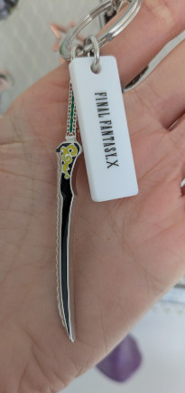 A metal charm in the shape of Auron’s sword